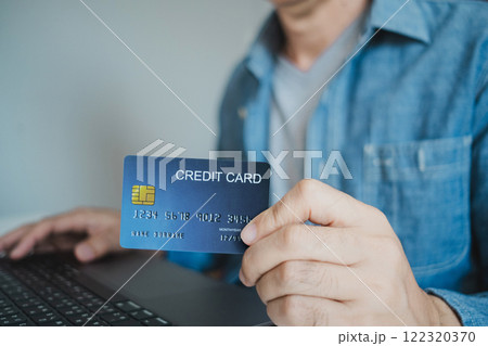 Close up, Man holding credit card while using laptop, shopping online, buying on internet. e-commerce e-banking service. Close up, Man holding credit card while using laptop, shopping online, buying on internet. e-commerce e-banking service. 122320370