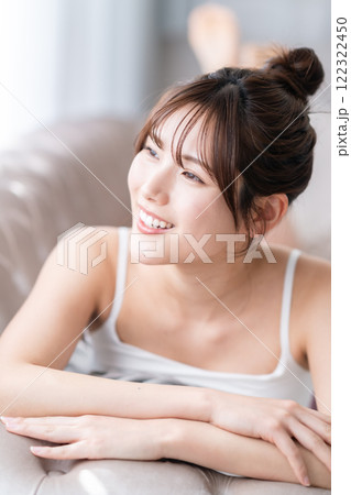 ソファーで窓の外を見ながら横になる若い女性 ソファーで窓の外を見ながら横になる若い女性 122322450