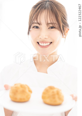 シュークリームを持って微笑むパティシエ シュークリームを持って微笑むパティシエ 122322467