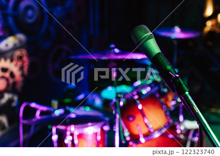 Close-up of a microphone illuminated by green neon light. Preparation for the concert. Drummer's place close-up. Rock concert in the bar.  122323740
