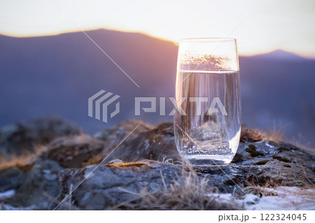 Pure natural drinking soda mineral water in a glass at the top of the mountain in winter. The frosty freshness of thirst A Refreshing Glass of Clear Water Against the Beautiful Backdrop of a Mountain Pure natural drinking soda mineral water in a glass at the top of the mountain in winter. The frosty freshness of thirst A Refreshing Glass of Clear Water Against the Beautiful Backdrop of a Mountain 122324045