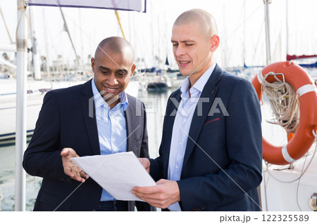 Two men in suits buy and sell a yacht in the seaport Two men in suits buy and sell a yacht in the seaport 122325589