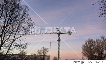 Construction crane with a long boom against the background of a light sky. Construction crane with a long boom against the background of a light sky. 122326234