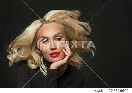 Stylish blond woman with makeup and perfect wavy hair posing on black studio wall background 122326662