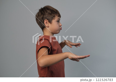 A child gestures playfully while making a humorous expression, captured from the side. The photo captures the joy and imagination of childhood. A child gestures playfully while making a humorous expression, captured from the side. The photo captures the joy and imagination of childhood. 122326783