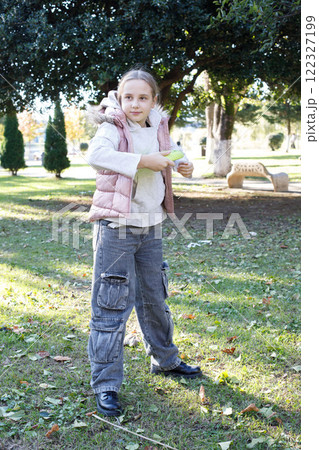 Pretty happy girl child playing flying disc in a sunny, green outdoor setting, exemplifying carefree 122327199