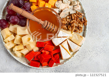 Appetizer, assorted cheese, with nuts and honey, on a round plate, top view, no people, Appetizer, assorted cheese, with nuts and honey, on a round plate, top view, no people, 122327521