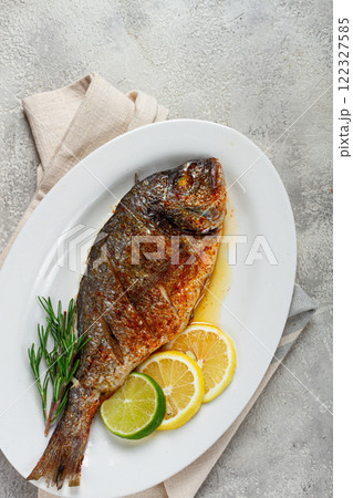 baked dorado fish, in the oven, fried dorado, with spices and herbs, on a white plate, top view, homemade, no people, 122327585