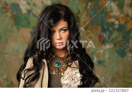 Gorgeous brunette woman posing in art studio. Young lady with long curly hair and make-up  122327667
