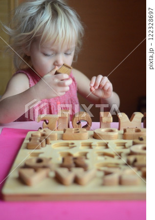 Little girl enthusiastically plays with wooden alphabet letters 122328697