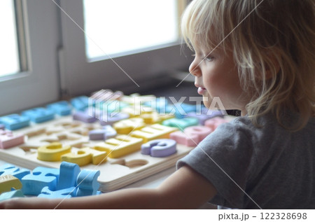 Little girl enthusiastically plays with colorful wooden alphabet letters 122328698