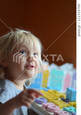 Little girl enthusiastically plays with colorful wooden alphabet letters 122328700