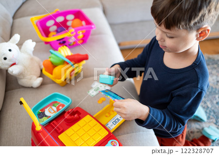 A child plays store with a toy cash register. A child plays store with a toy cash register. 122328707