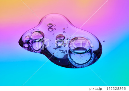 A drop of cosmetic serum on a multicolored background in shades of blue and lilac. 122328866