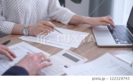 Bookkeeper woman is working with a colleague, using magnificent glass, calculator and laptop. Audit and taxes concept Bookkeeper woman is working with a colleague, using magnificent glass, calculator and laptop. Audit and taxes concept 122329743