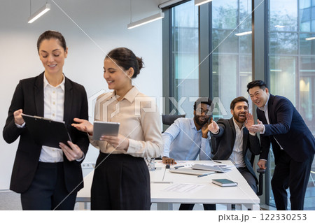 Unethical behavior, harassment. Men mocking female colleagues inside the office. Unethical behavior, harassment. Men mocking female colleagues inside the office. 122330253
