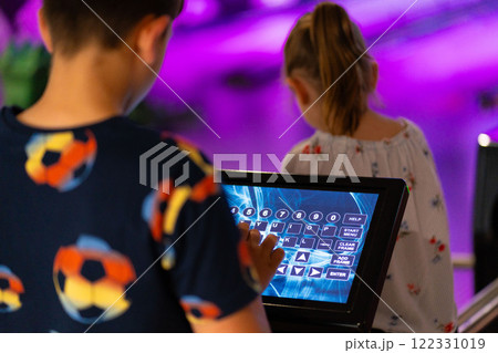 Primary school boy using big touch screen display and delighted looking around. Children and modern technology concepts. 122331019