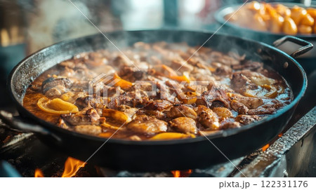 Juicy meat sizzling in a large pan outdoors 122331176