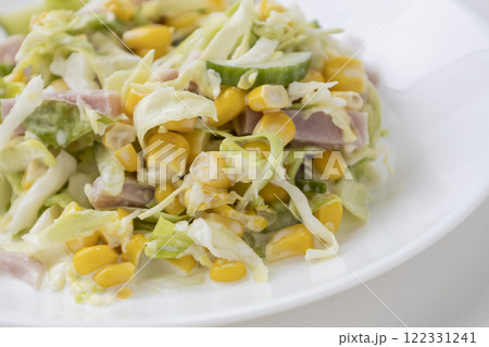 Tasty and healthy salad with cabbage, cucumber, corn, ham and mayonnaise on a white plate. Tasty and healthy salad with cabbage, cucumber, corn, ham and mayonnaise on a white plate. 122331241