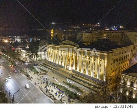 Drone view on Georgian Parliament building and night city behind Drone view on Georgian Parliament building and night city behind 122331249