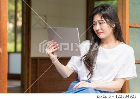 タブレットで動画配信を見て感動する若い女性 122334925