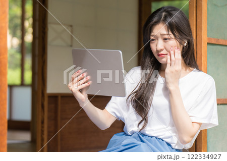 タブレットで動画配信を見て感動する若い女性 タブレットで動画配信を見て感動する若い女性 122334927