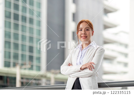 Confident businesswoman with crossed arms posing in front of a modern office building 122335115