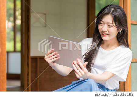 古民家でタブレットを見て笑っている若い女性 122335192