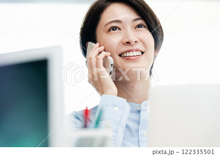 オフィスで通話するビジネスウーマン オフィスで通話するビジネスウーマン 122335501