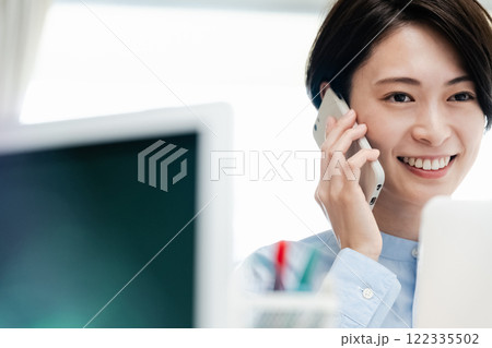 オフィスで通話するビジネスウーマン オフィスで通話するビジネスウーマン 122335502