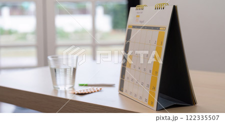 Monthly calendar displayed with a water glass and contraceptive pills, symbolizing family planning Monthly calendar displayed with a water glass and contraceptive pills, symbolizing family planning 122335507