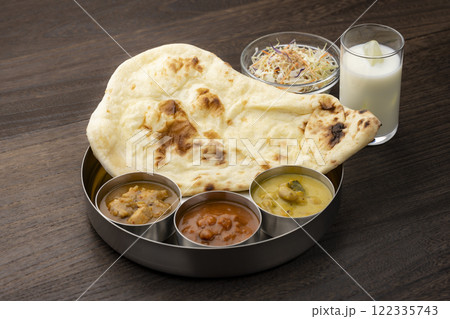 サラダとラッシーが添えられたナンと3種類のカレーセット 122335743