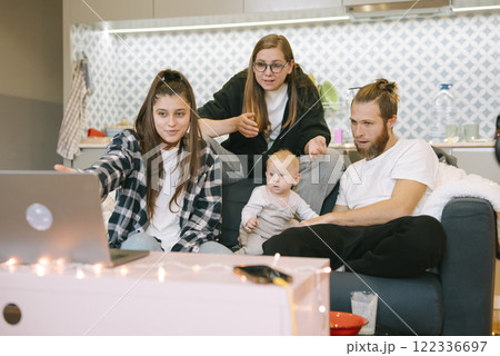 A family gathering occurs, where a baby engages with a laptop while being watched by loved ones 122336697