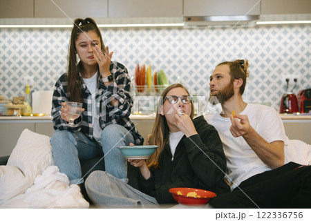 A group of friends joyfully enjoying delicious snacks together in the comfort of home A group of friends joyfully enjoying delicious snacks together in the comfort of home 122336756