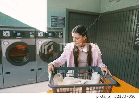 A Young Woman Happily Doing Laundry in a Bright and Modern Laundromat Environment A Young Woman Happily Doing Laundry in a Bright and Modern Laundromat Environment 122337086