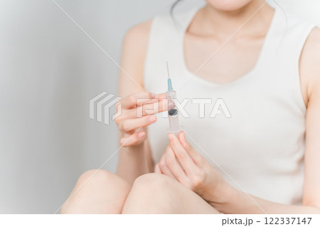 注射器を叩いて空気を抜く女性 122337147