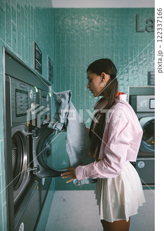 A Young Woman Engaged in Laundry Activities at a Modern and Trendy Laundromat Facility 122337166