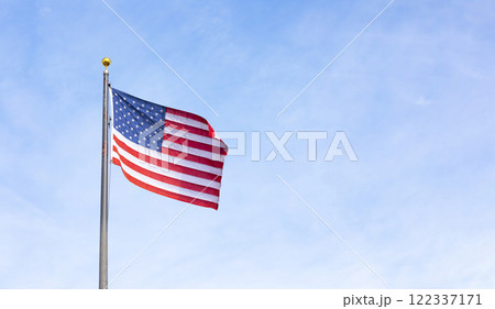 American Flag Waving Proudly On Flagpole Against Blue Sky. Flag With Stars And Stripes Symbolizing Freedom, Patriotism, National Pride. United States, Independence Day, Memorial Day Or Veterans Day 122337171