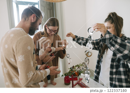 Family members joyfully celebrating together indoors, surrounded by festive holiday decorations Family members joyfully celebrating together indoors, surrounded by festive holiday decorations 122337180