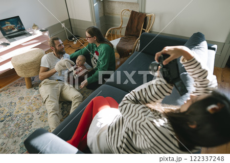 A Group of Friends Enjoying a Cozy and Comfortable Indoor Moment with a Baby and a Camera 122337248
