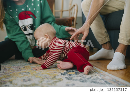 A joyful crawling baby enjoys time with family in a cozy holiday setting full of cheer A joyful crawling baby enjoys time with family in a cozy holiday setting full of cheer 122337317