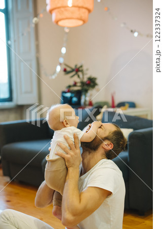 A Joyful and Loving Father Enjoys Playtime with His Baby at Their Cozy Home Together 122337324