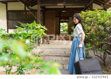キャリーケースを引いて田舎に帰省する若い女性　旅行イメージ 122337441
