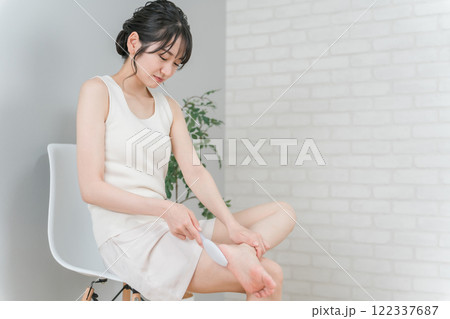 かかとにヤスリをかけてフットケアをする笑顔のアジア人女性 かかとにヤスリをかけてフットケアをする笑顔のアジア人女性 122337687