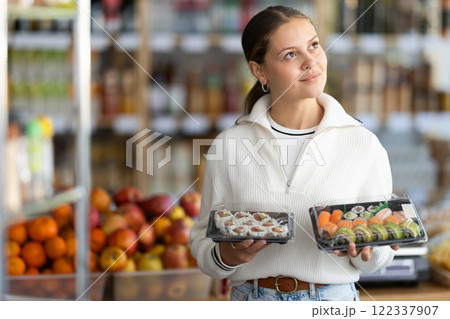 Young woman choosing packaged sushi and rolls 122337907