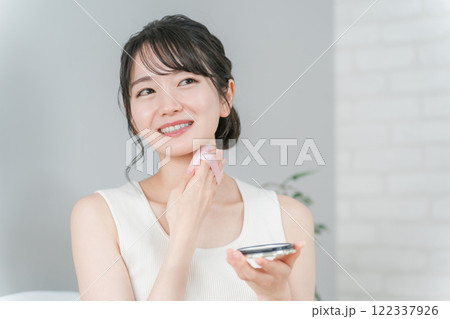 首に日焼け止め・制汗のボディーパウダーをパフで塗るアジア人女性 122337926