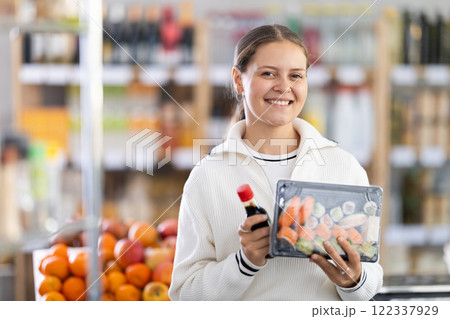 Grocery shopping at supermarket - woman chooses soy sauce for sushi Grocery shopping at supermarket - woman chooses soy sauce for sushi 122337929
