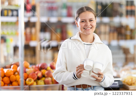 Woman chooses tasty yogurt to buy in the grocery department section of store Woman chooses tasty yogurt to buy in the grocery department section of store 122337931