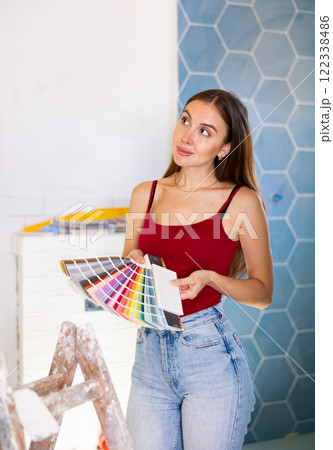 Beautiful young woman choosing tiles color samples in apartment 122338486