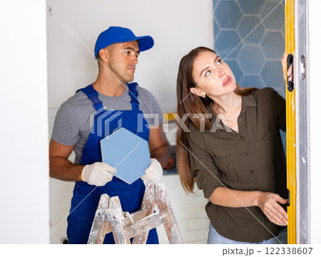 Woman using spirit level on wall with repairman Woman using spirit level on wall with repairman 122338607